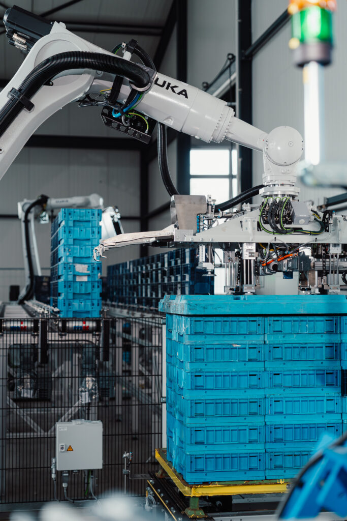 Robotergreifarm palettiert blaue Kisten.