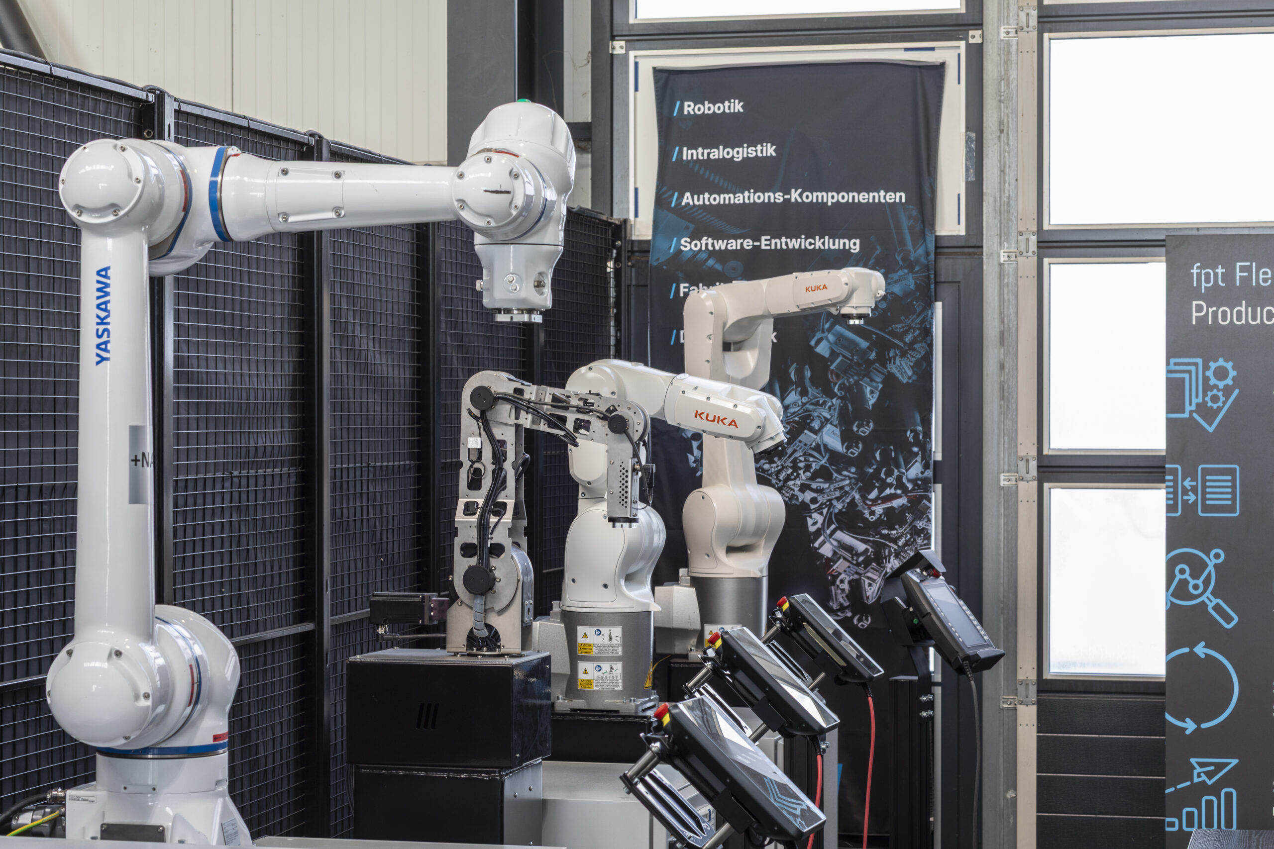 Vier Roboter unterschiedlicher Hersteller im Vordergrund mit Smartpad als Bedienelemente