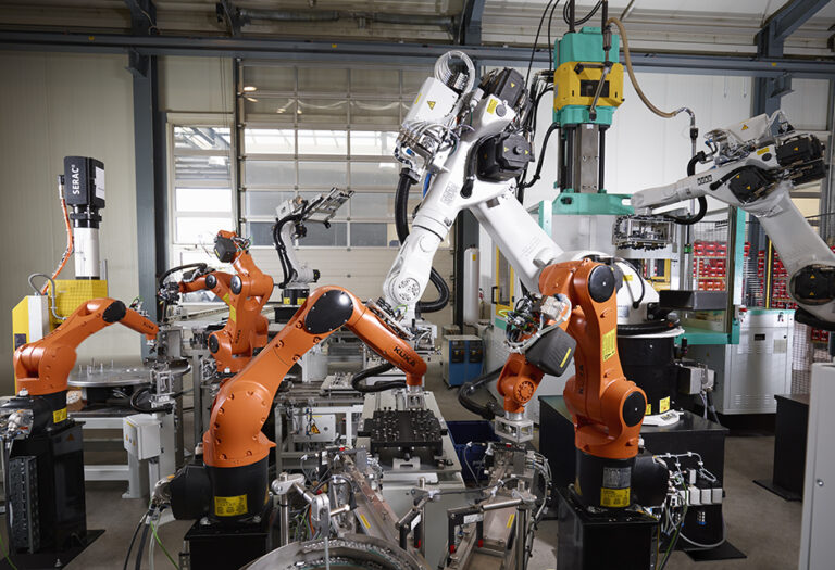 Anlage mit mehreren Industrierobotern, die gleichzeitig vor und an einer Spritzgießmaschine arbeiten, in verschiedenen Größen und Farben