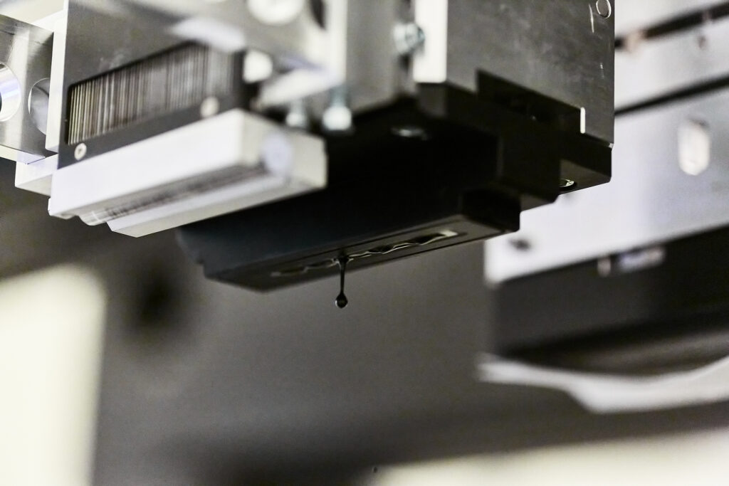 Black print head with a single ink drop behind UV curing