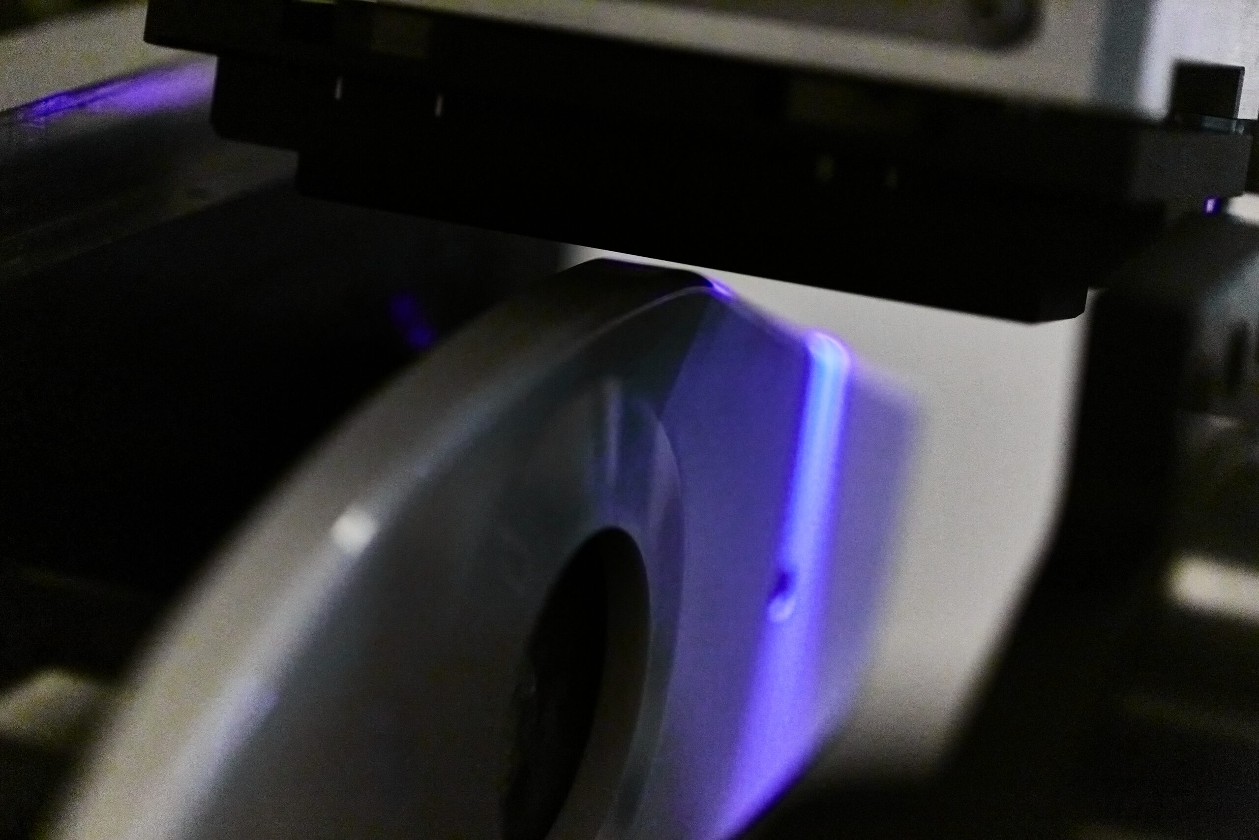 A plastic component moves under a print head and is treated with UV.