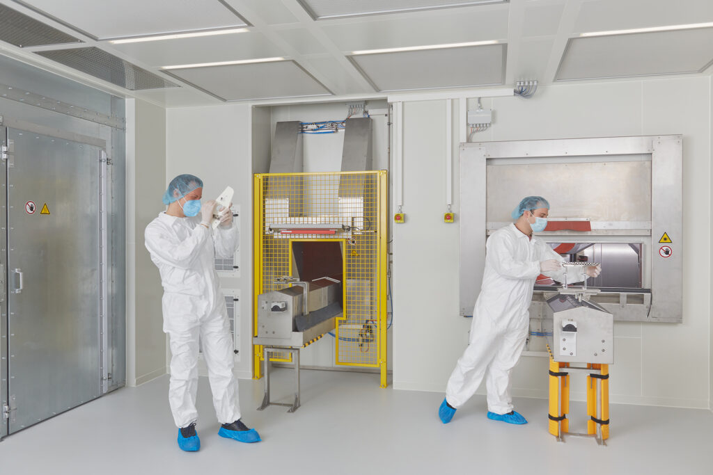 Two men in protective suits in the cleanroom during a quality process in the printing process