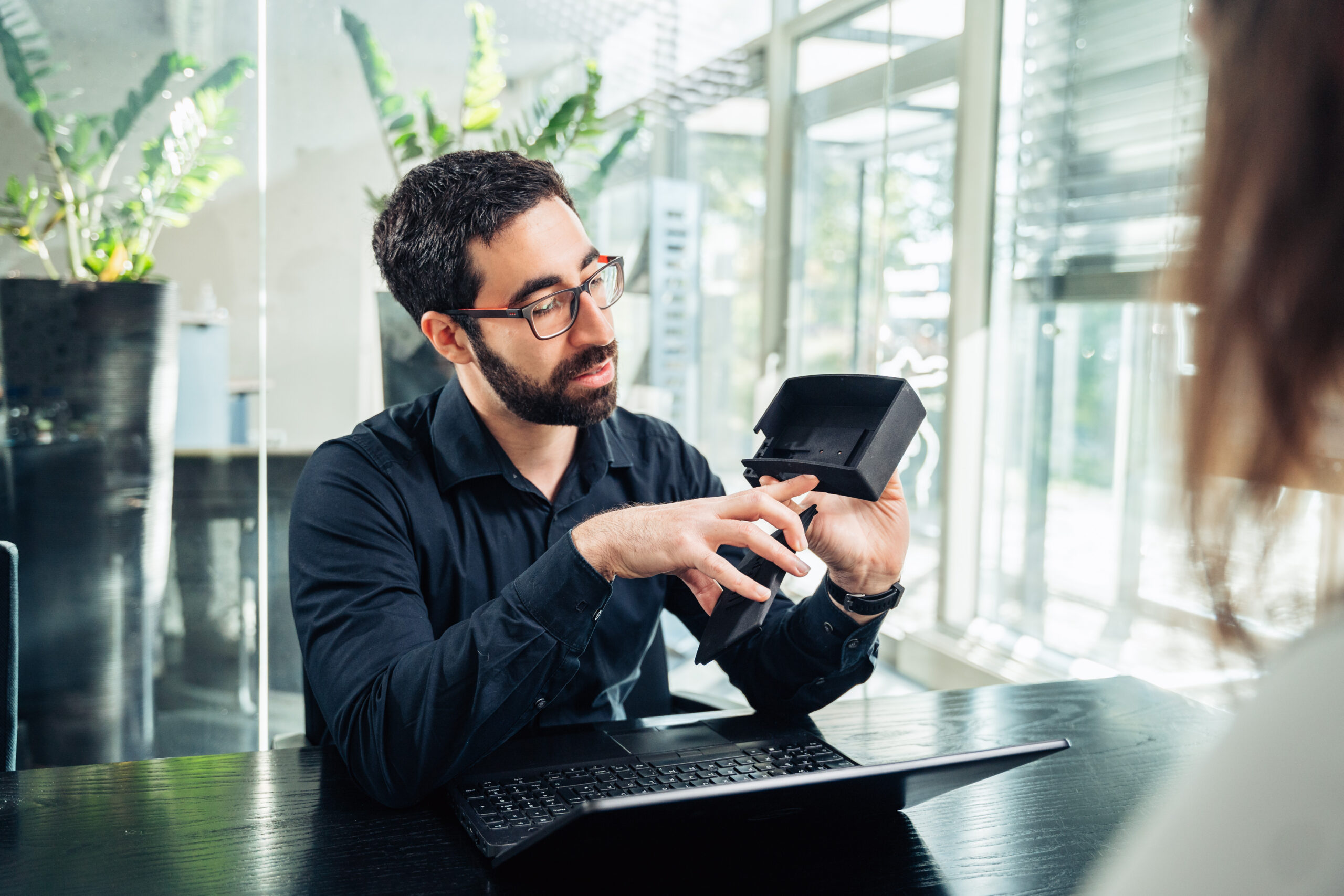 Man in a black shirt shows a woman a 3D printed component