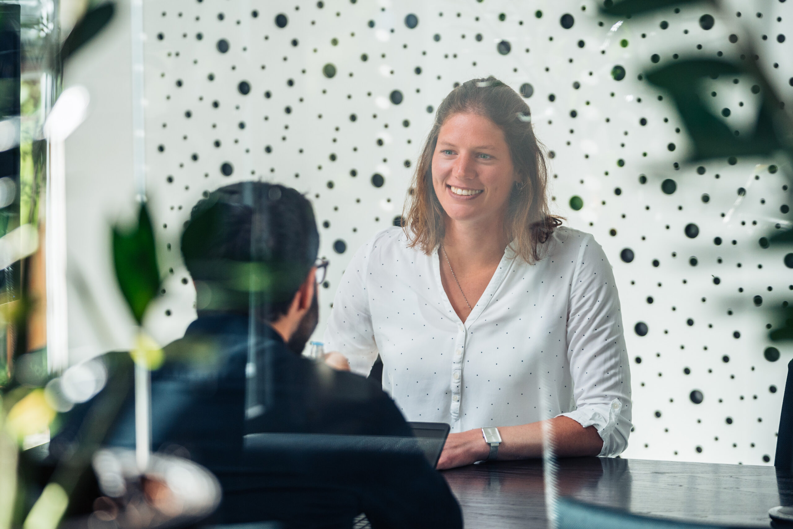 A woman in a white blouse conducts a job interview with a man in a dark shirt