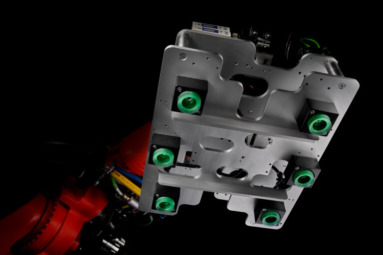 Dunkle stimmungsvolle Szenerie eines Robotergreifers mit Saugnäpfen an einem orangen Roboterarm