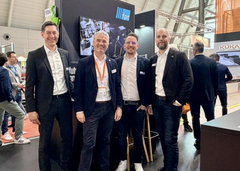 Vier Männer stehen im Anzug auf der LogiMAT in Stuttgart vor dem Messestand von fpt robotics.