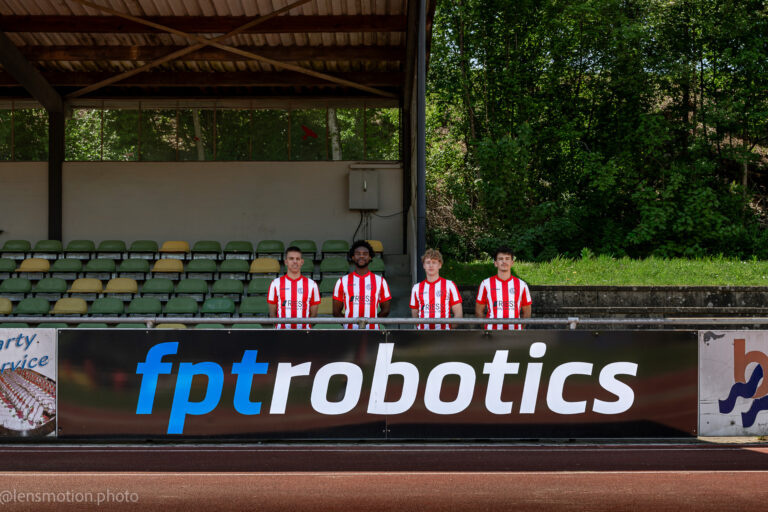 Fußballspieler in Rot-Weiß hinter einer neuen Werbebande mit dem Schriftzug von "fpt robotics" stehend