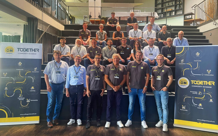 Eine Gruppe von Menschen auf einer dunklen Treppe sitzend mit Interroll-Bannern rechts und links
