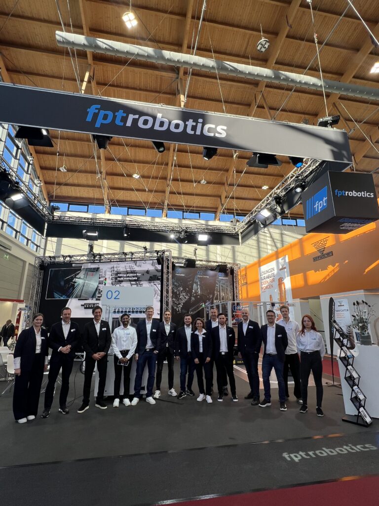 Teamfoto von Mitarbeitern der FPT Robotik GmbH & Co. KG auf der Fakuma-Messe in Friedrichshafen