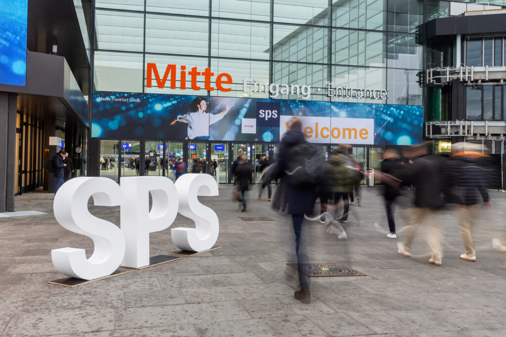 Eingangsbereich einer Halle der SPS-Messe in Nürnberg. Größe weiße "SPS" Buchstaben vor den Eingangstüren.